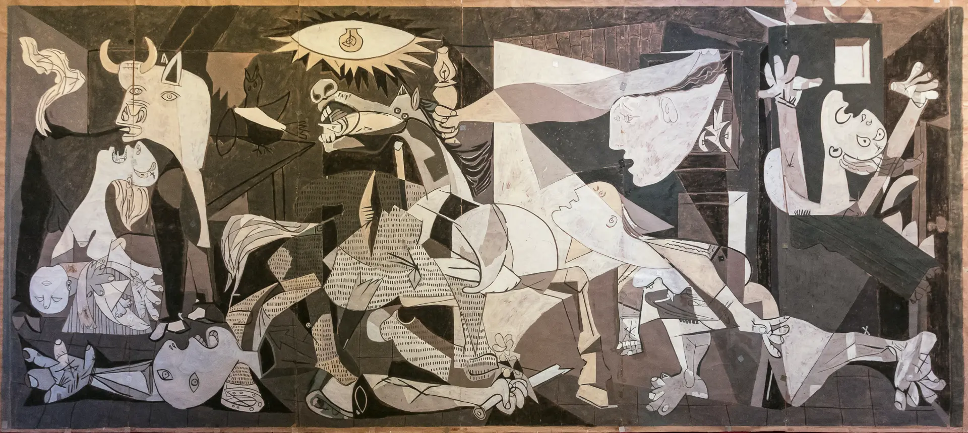 Dettaglio di Guernica di Pablo Picasso: volti urlanti, braccia alzate e corpi caduti resi in tonalità di grigio.