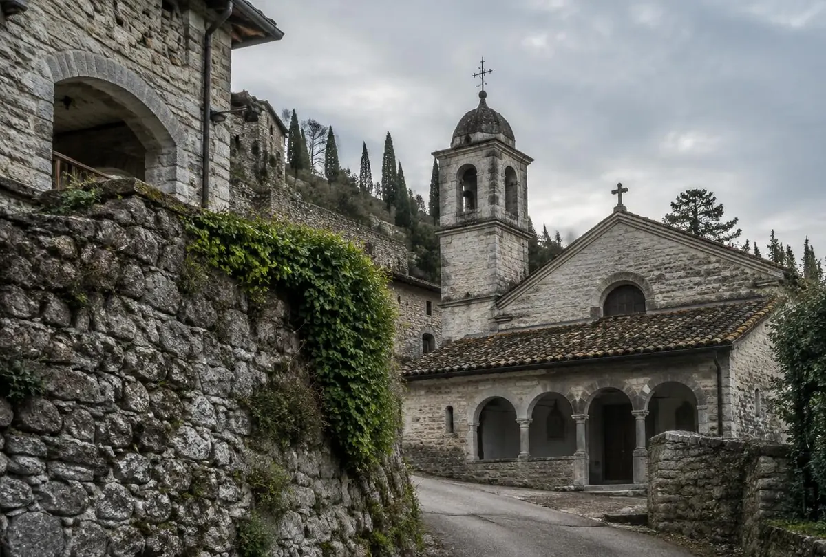 Antico borgo di Artegna: campanile in pietra fra cipressi e muri coperti di edera.